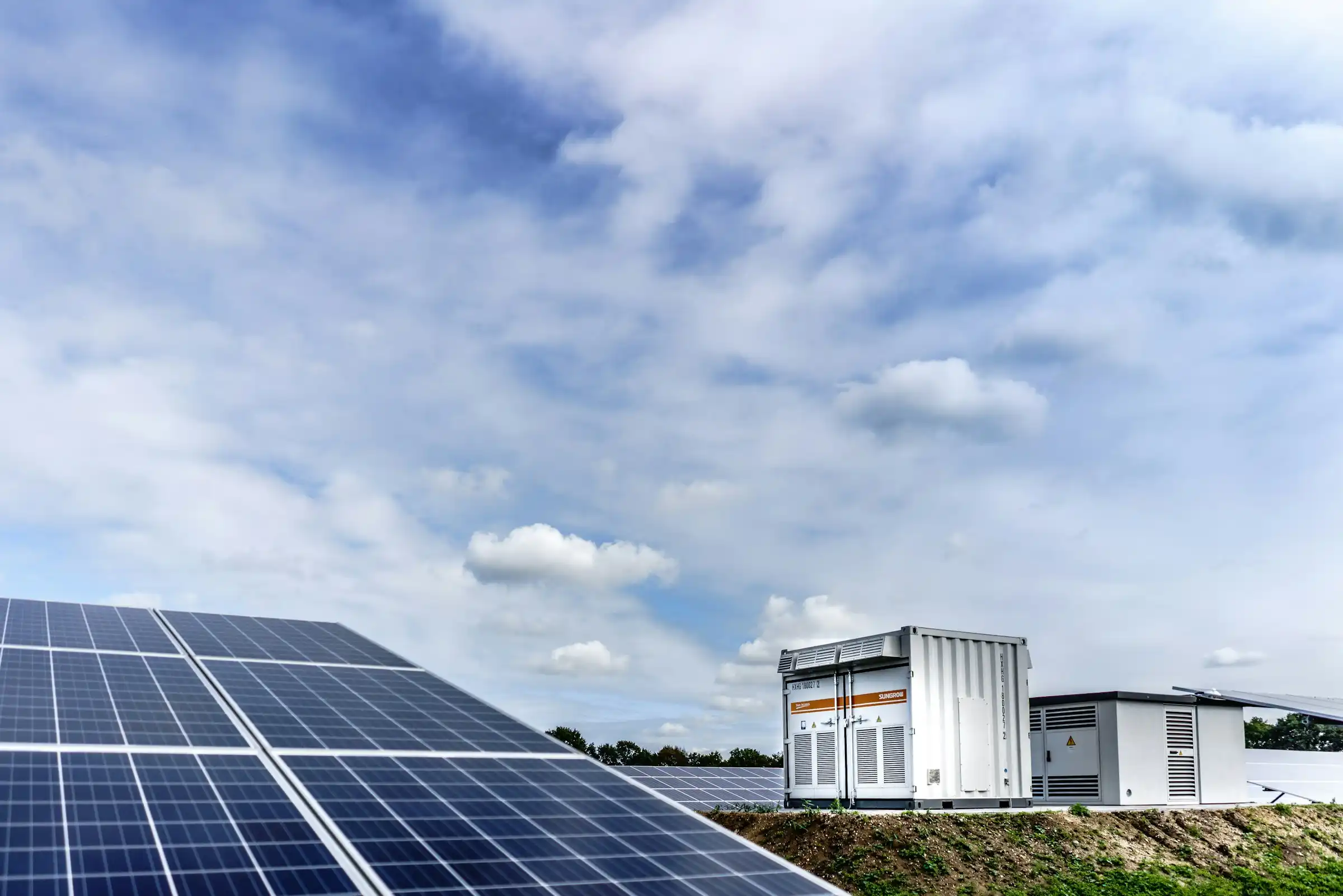 Battery storage units beside rows of solar panels