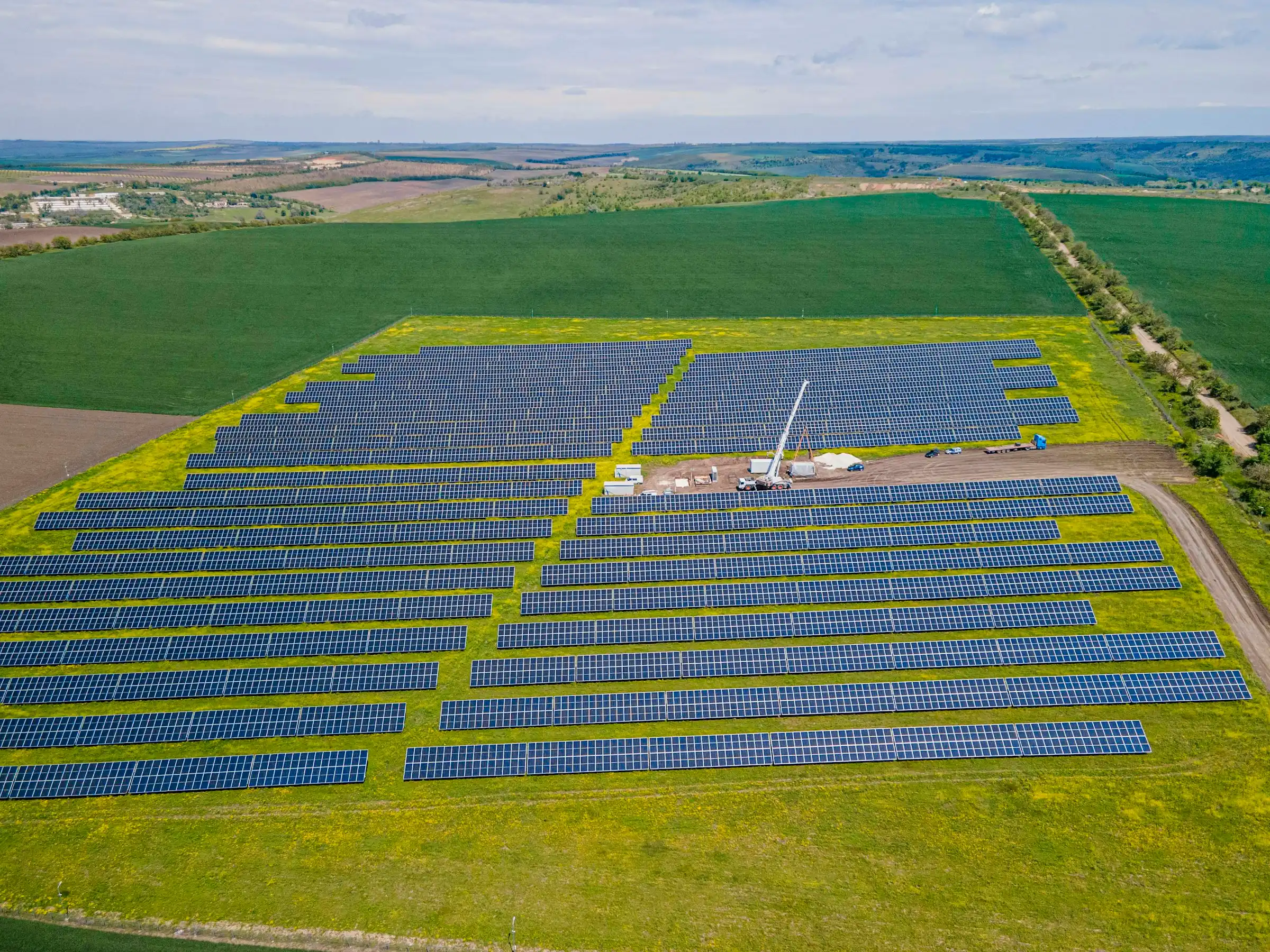 Aerial view of a large solar farm surrounded by green fields