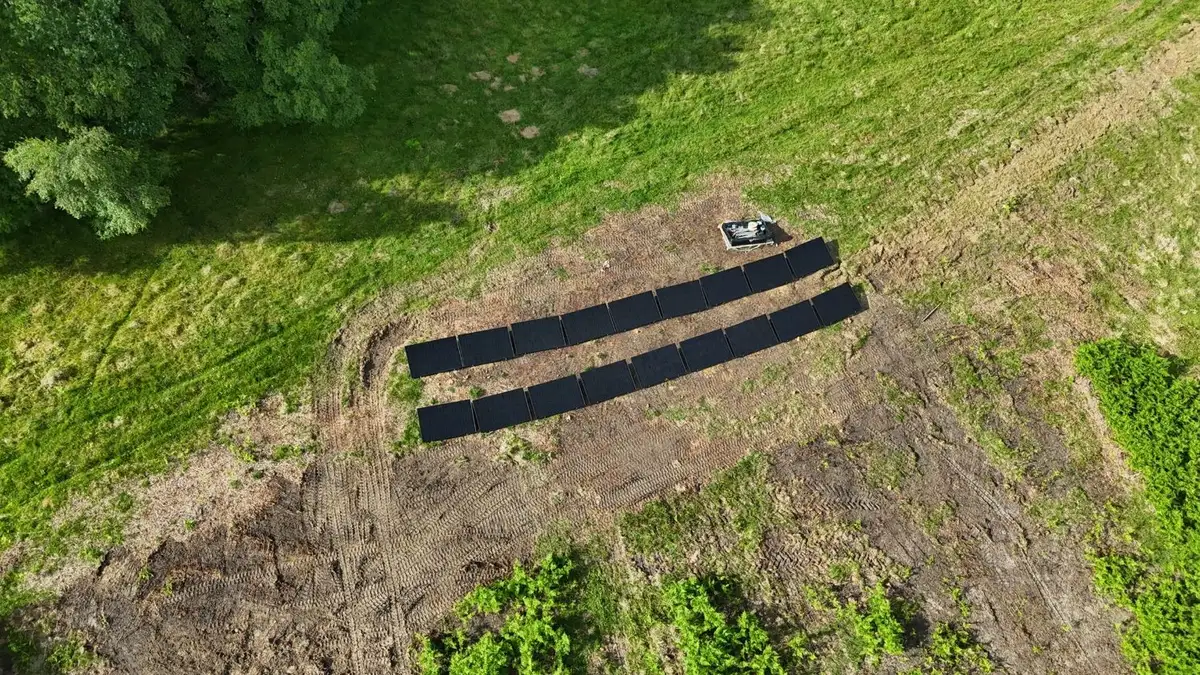 Drone view of two rows of ground-mounted solar panels in a green field in Devon, installed by Quanta